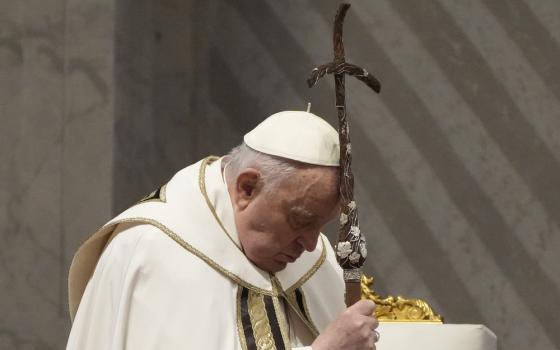 Pope Francis leans head on processional crucifix.